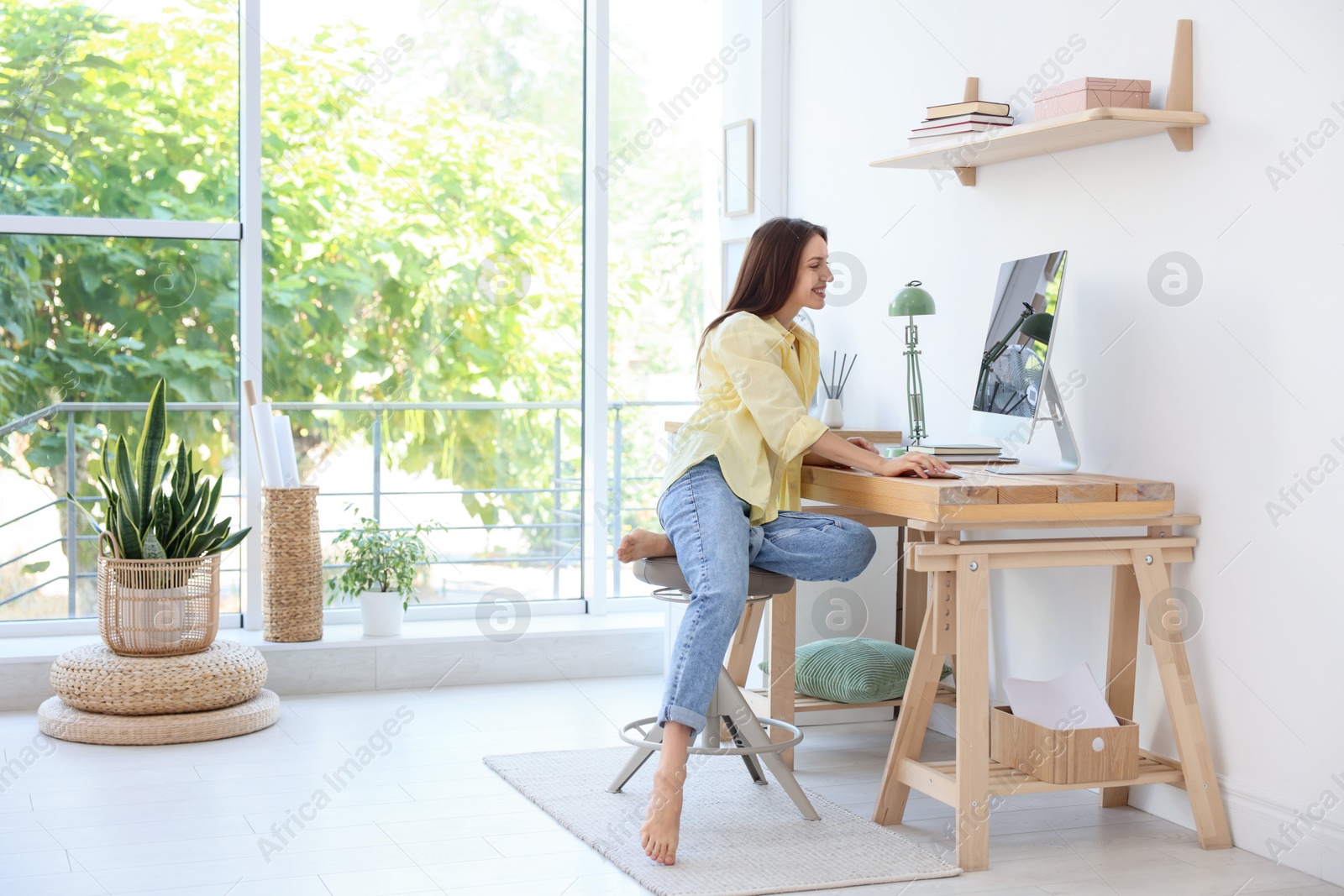 Photo of Woman using computer at wooden desk indoors, space for text. Home workplace