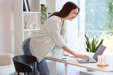 Photo of Woman using computer at wooden desk indoors. Home workplace