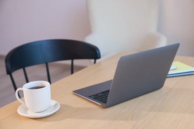 Photo of Home workspace. Modern laptop and stationery on wooden desk indoors