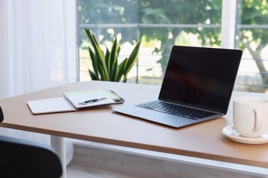 Photo of Home workspace. Modern laptop and stationery on wooden desk indoors