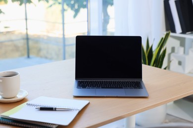 Photo of Home workspace. Modern laptop and stationery on wooden desk indoors