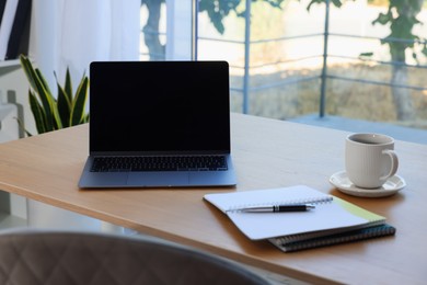 Photo of Home workspace. Modern laptop and stationery on wooden desk indoors