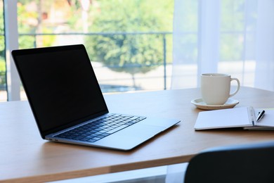 Photo of Home workspace. Modern laptop and stationery on wooden desk indoors