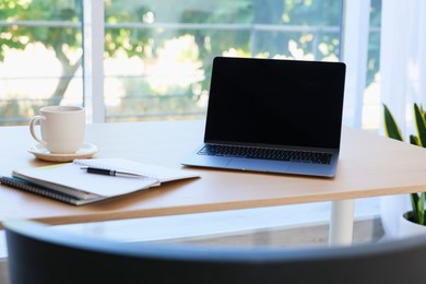 Photo of Home workspace. Modern laptop and stationery on wooden desk indoors