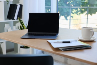 Photo of Home workspace. Modern laptop and stationery on wooden desk indoors