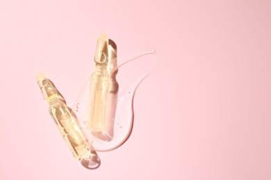 Photo of Glass ampoules with cosmetic product on pink background, flat lay. Space for text