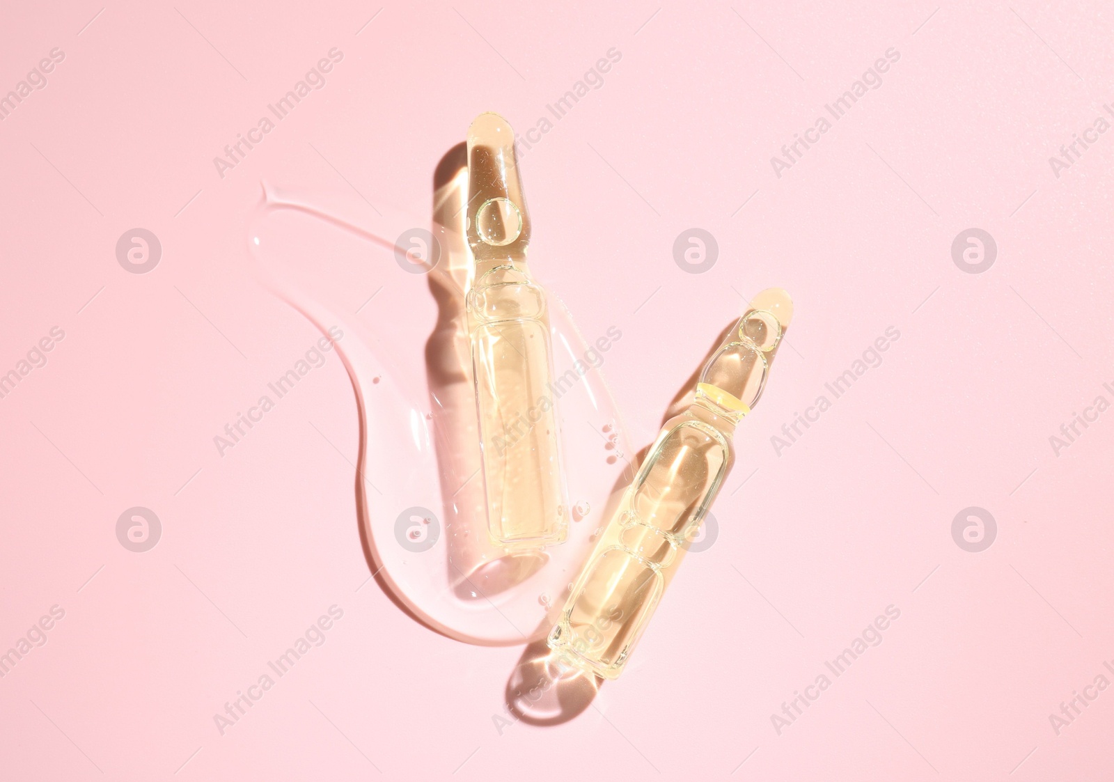 Glass ampoules with cosmetic product on pink background, flat lay Photo of Glass ampoules with cosmetic product on pink background, flat lay
