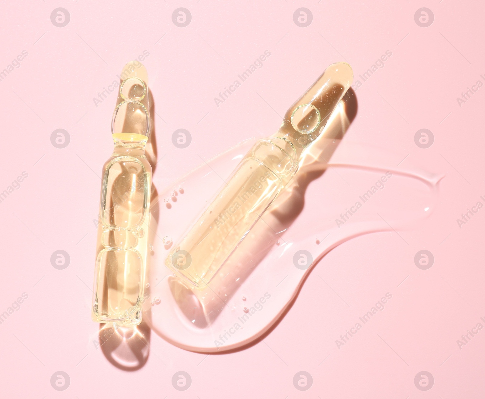 Glass ampoules with cosmetic product on pink background, flat lay Photo of Glass ampoules with cosmetic product on pink background, flat lay