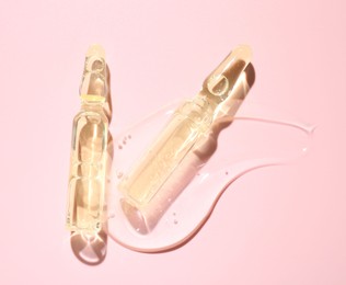 Photo of Glass ampoules with cosmetic product on pink background, flat lay