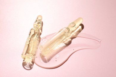 Photo of Glass ampoules with cosmetic product on pink background, closeup
