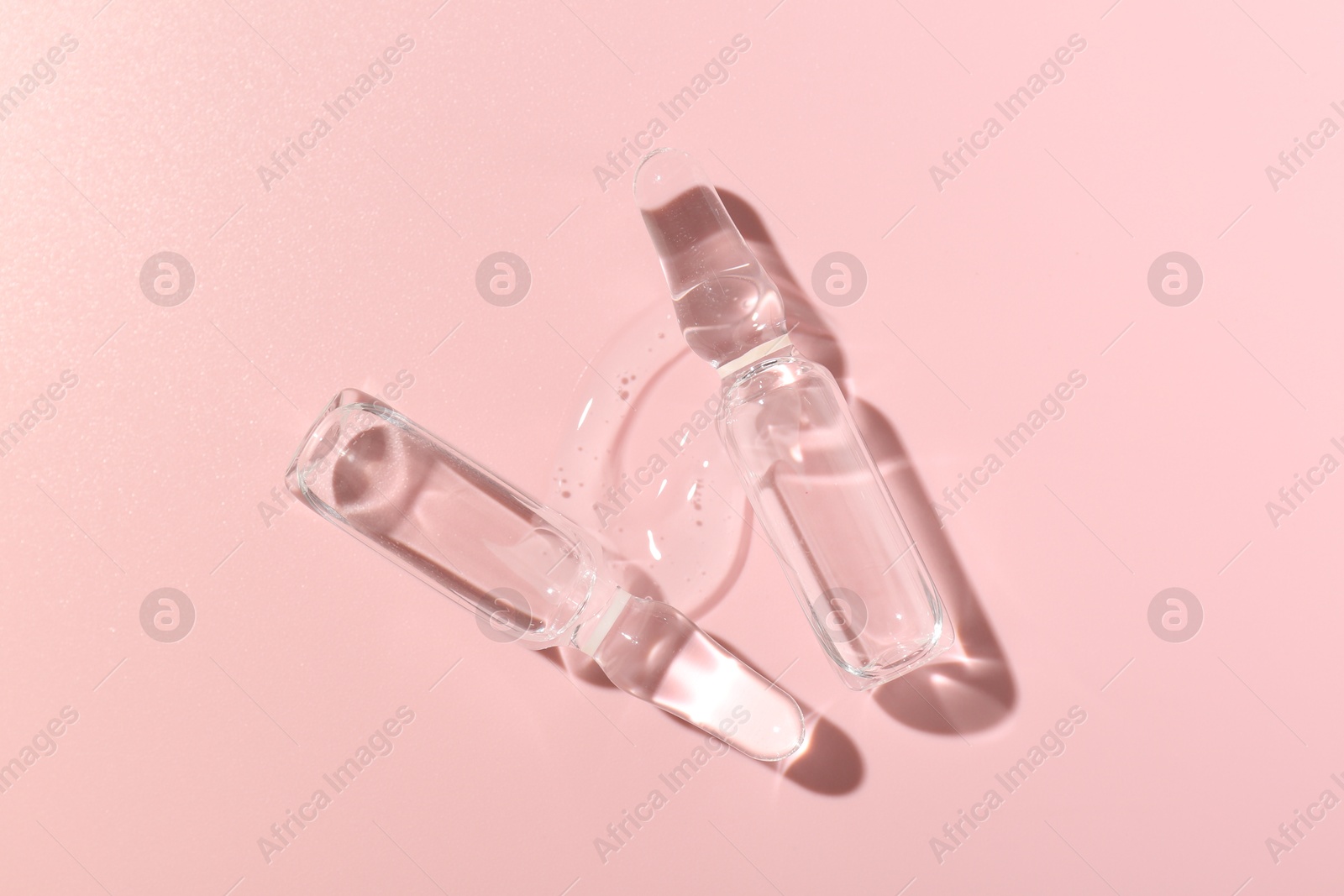 Glass ampoules with cosmetic product on pink background, flat lay Photo of Glass ampoules with cosmetic product on pink background, flat lay