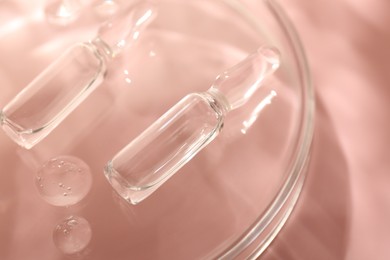 Photo of Glass ampoules with cosmetic product and Petri dish on pink background, closeup