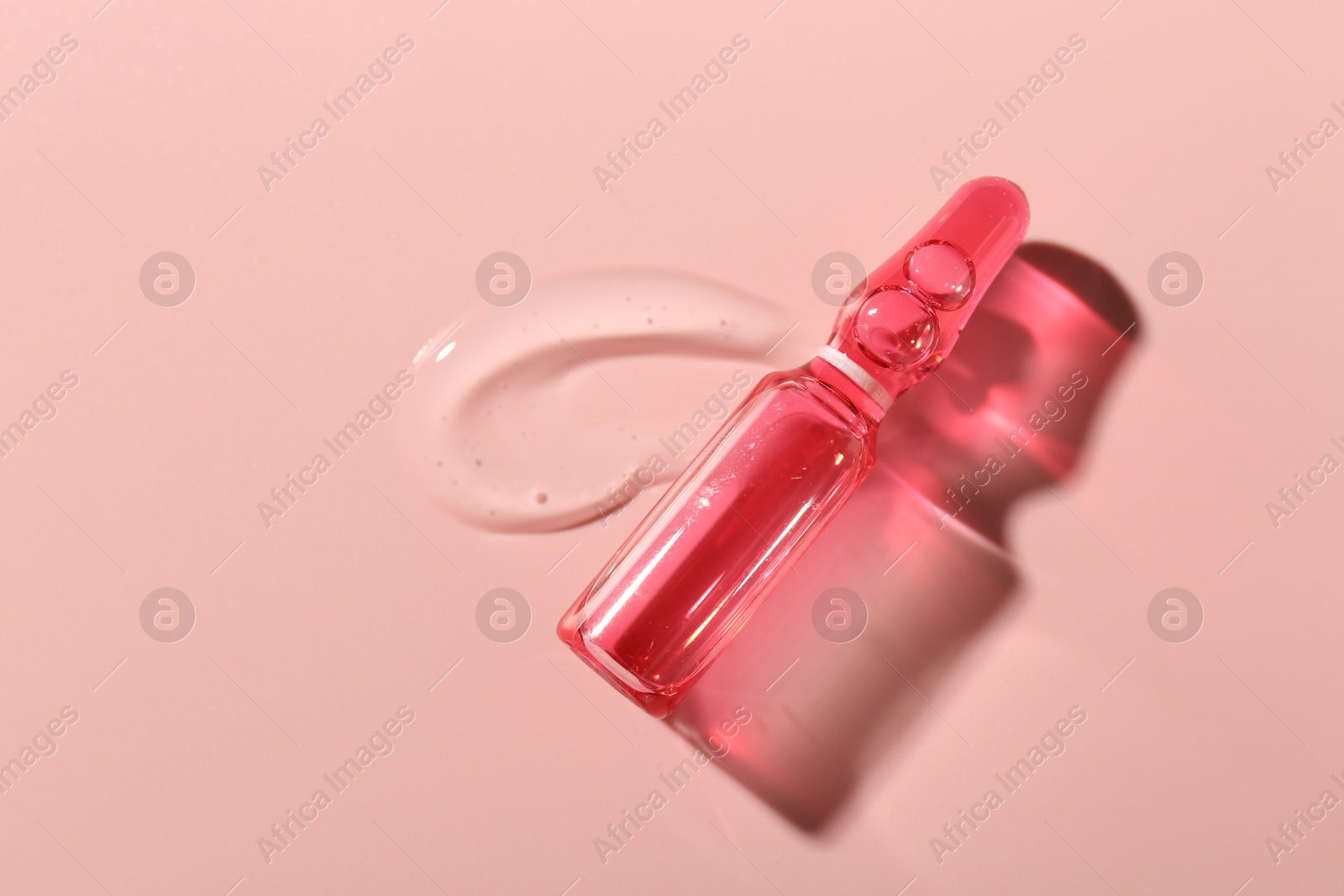 Glass ampoule with cosmetic product on pink background, top view Photo of Glass ampoule with cosmetic product on pink background, top view