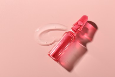 Photo of Glass ampoule with cosmetic product on pink background, top view