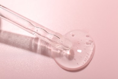 Photo of Dripping cosmetic product from pipette on pink background, closeup