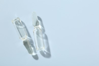 Photo of Glass ampoules with cosmetic product on light blue background, flat lay. Space for text