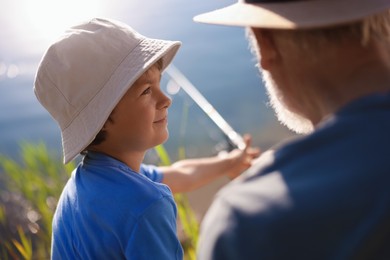 Photo of Grandfather and his nephew fishing together outdoors, closeup
