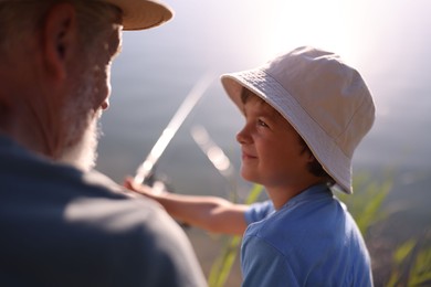 Photo of Grandfather and his nephew fishing together outdoors, closeup