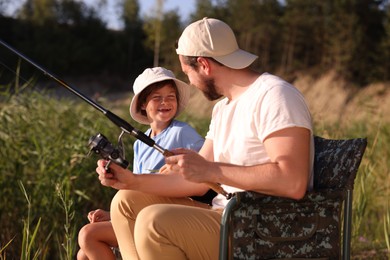 Photo of Father and his happy little son fishing together outdoors
