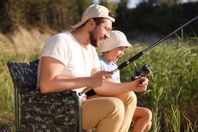 Photo of Father and his happy little son fishing together outdoors