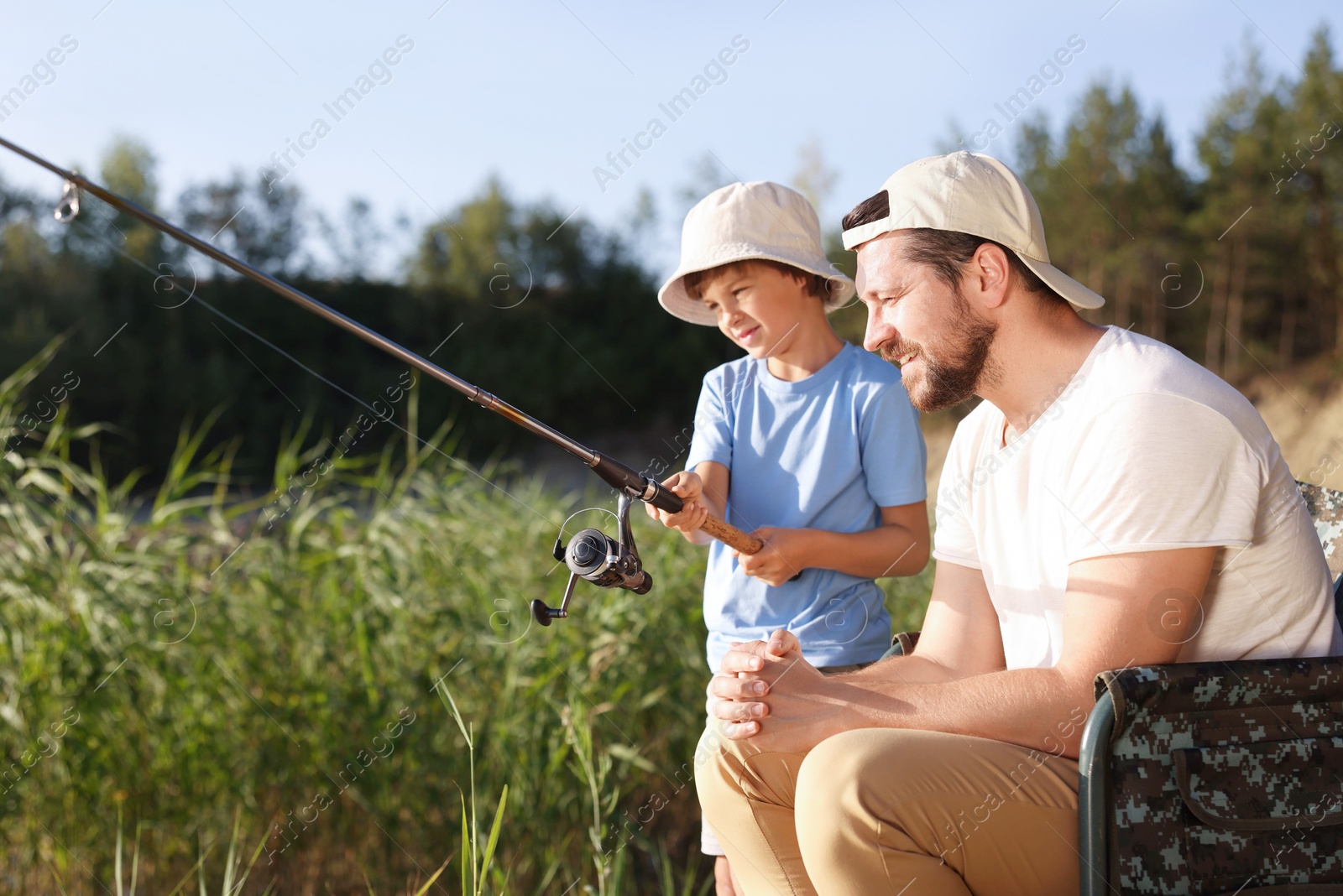 Photo of Happy father and his little son fishing together outdoors
