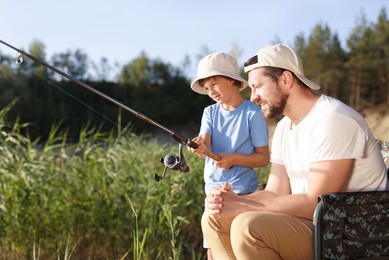 Photo of Happy father and his little son fishing together outdoors