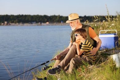 Photo of Grandfather and his nephew fishing together near river outdoors