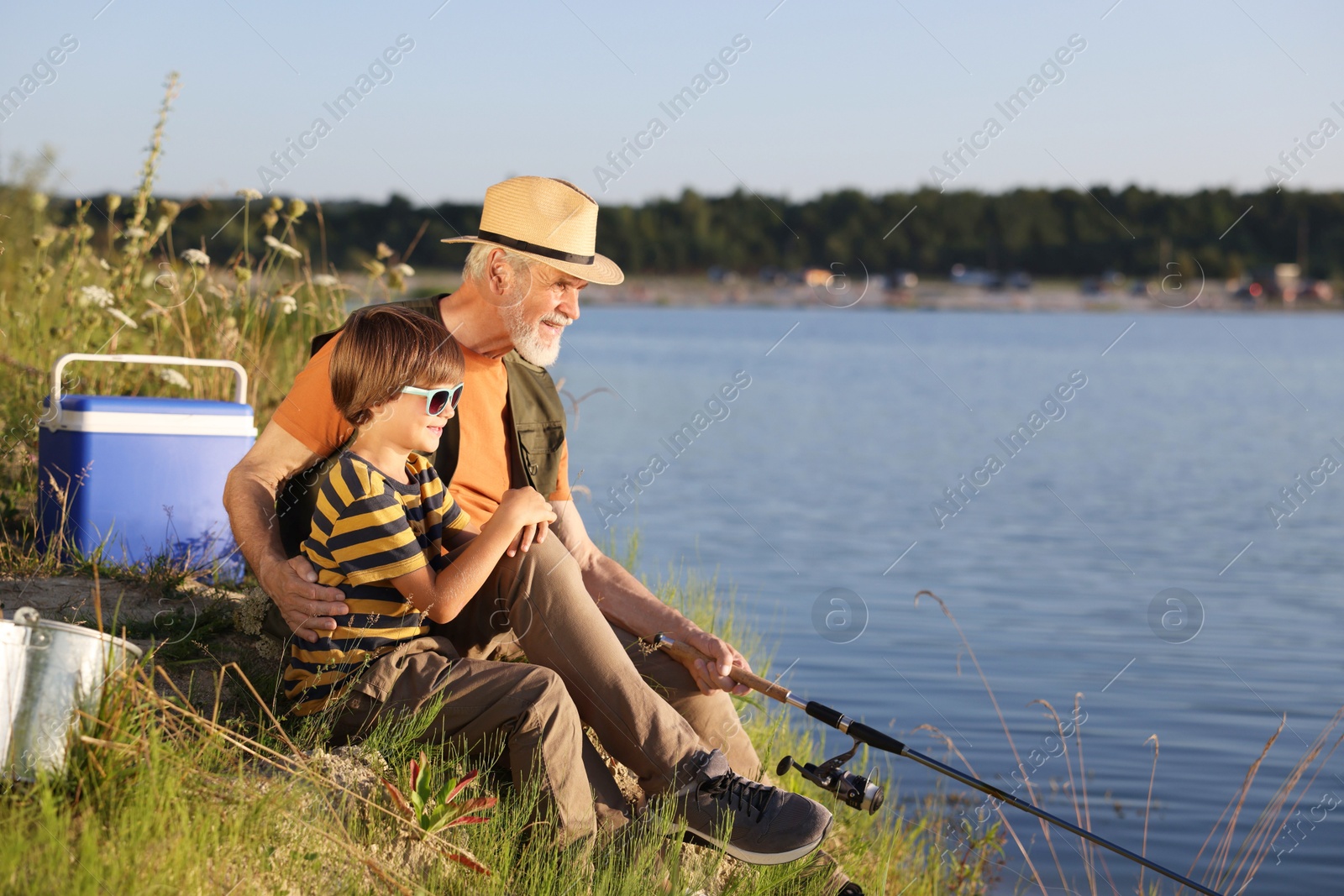 Photo of Grandfather and his nephew fishing together near river outdoors