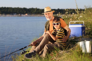 Photo of Grandfather and his nephew fishing together near river outdoors