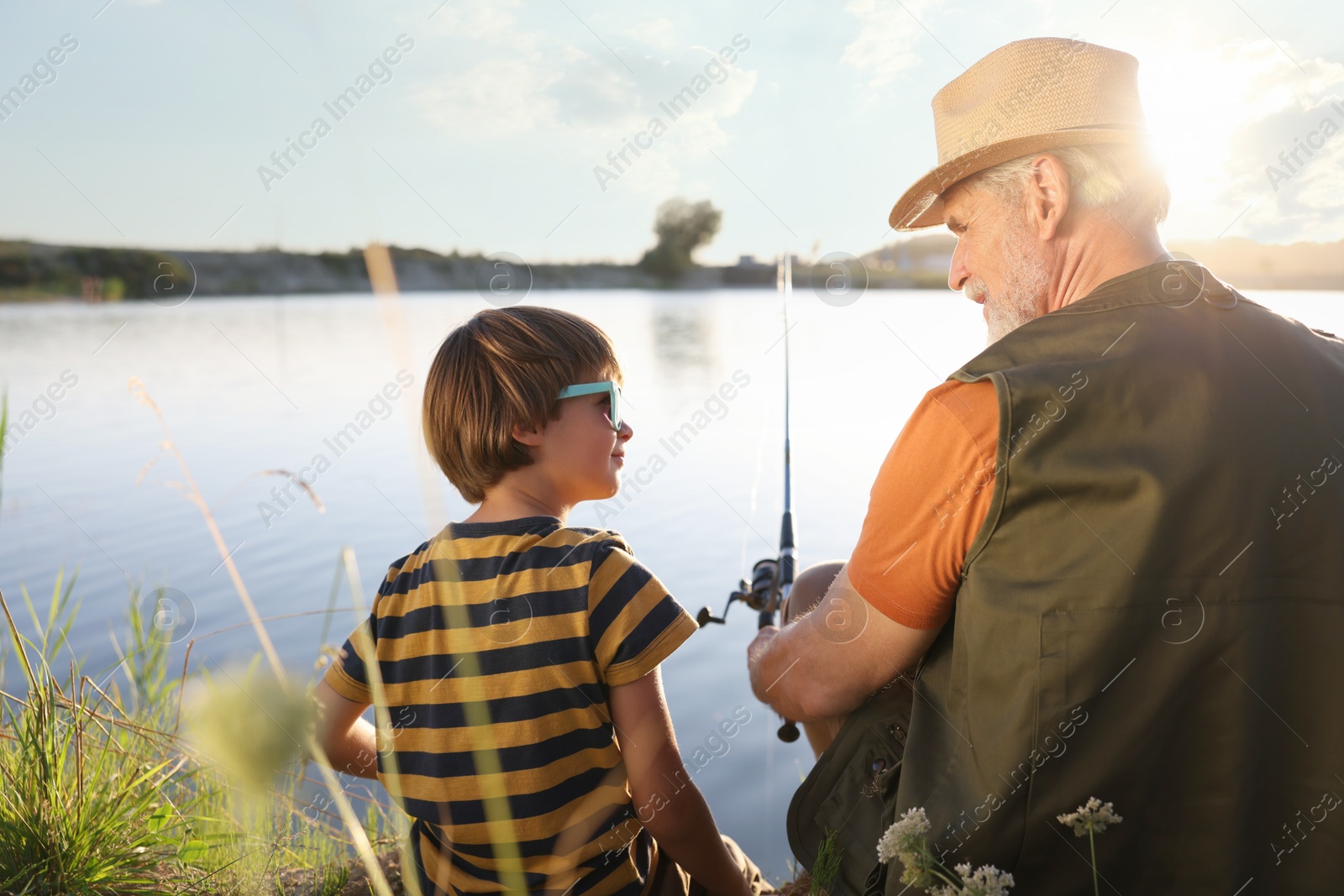Photo of Grandfather and his nephew fishing together near river outdoors