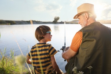 Photo of Grandfather and his nephew fishing together near river outdoors