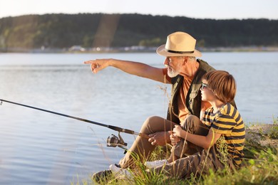 Photo of Grandfather and his nephew fishing together near river outdoors