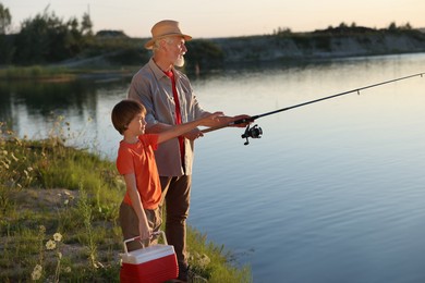 Photo of Grandfather and his nephew fishing together near river outdoors