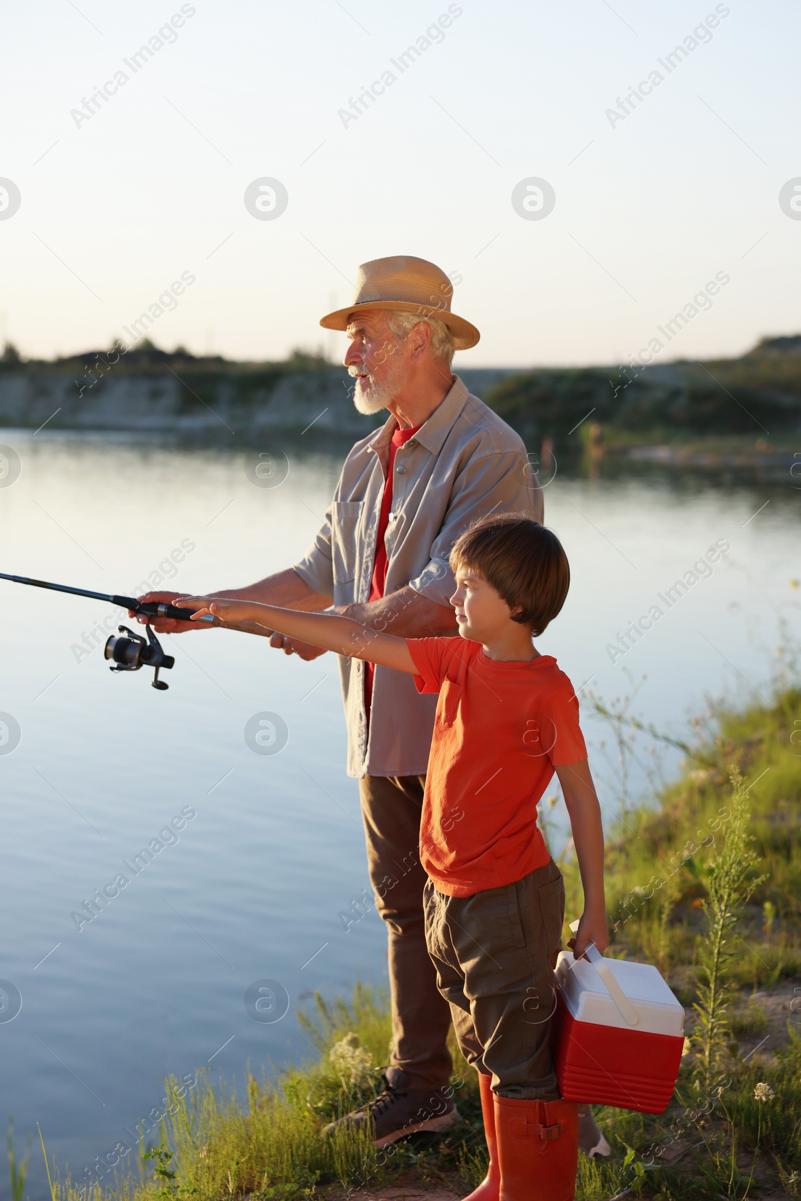 Photo of Grandfather and his nephew fishing together near river outdoors