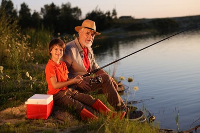 Photo of Grandfather and his nephew fishing together near river outdoors