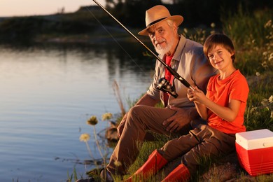 Photo of Grandfather and his nephew fishing together near river outdoors