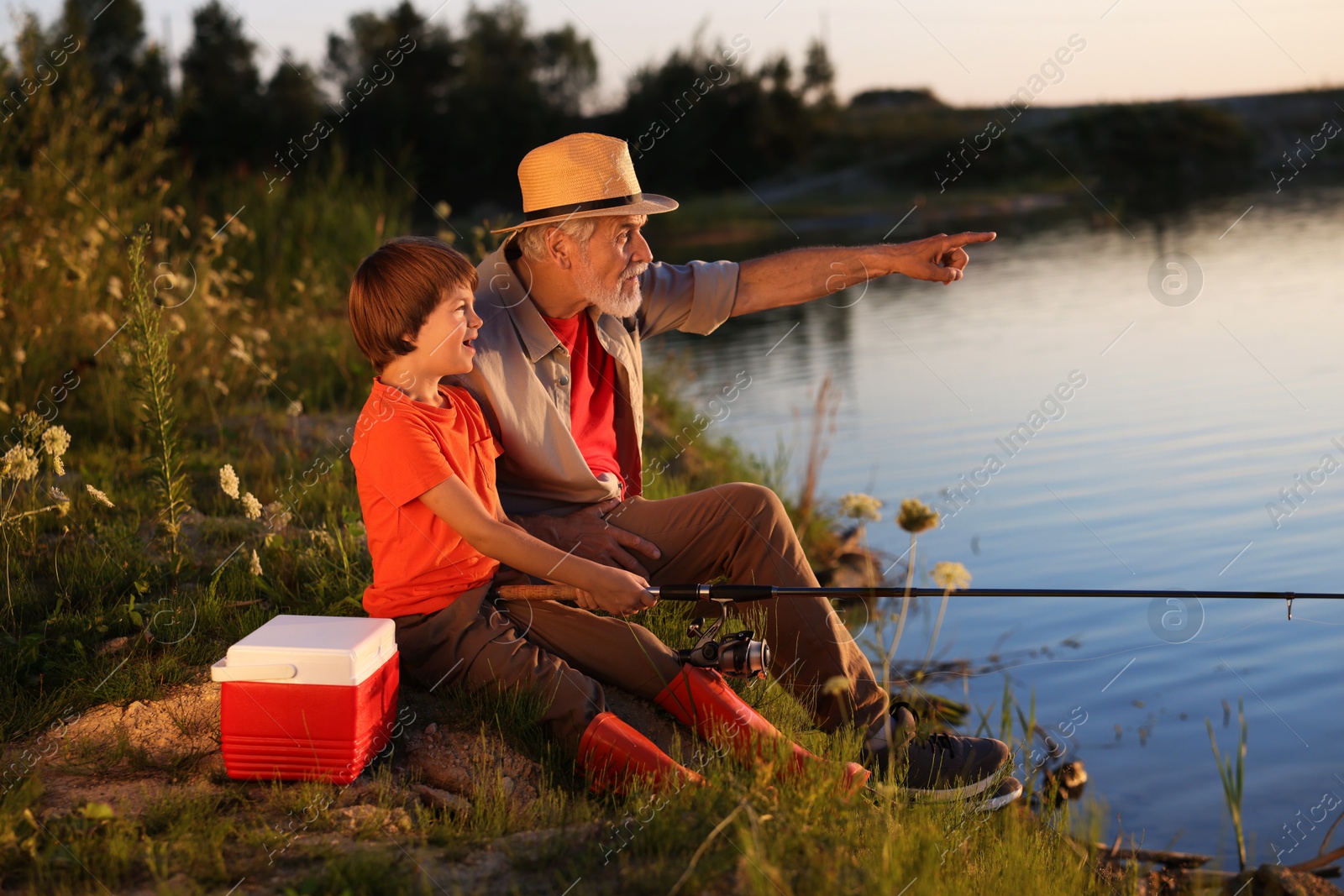Photo of Grandfather and his nephew fishing together near river outdoors