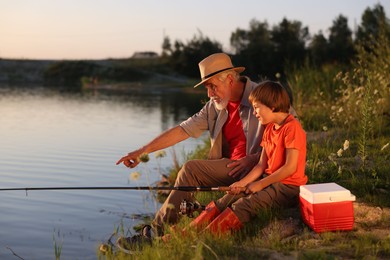 Photo of Grandfather and his nephew fishing together near river outdoors