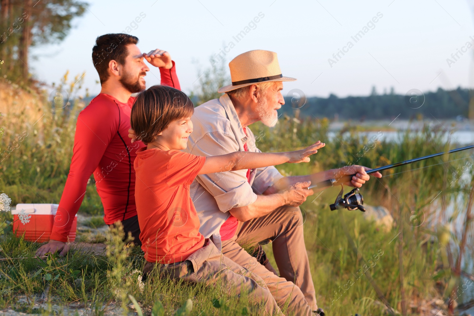 Grandfather, father and his little son fishing together outdoors Photo of Grandfather, father and his little son fishing together outdoors