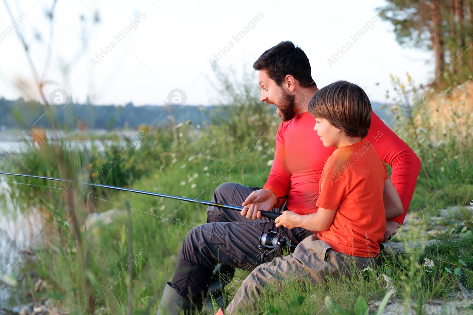 Photo of Emotional father and his little son fishing together outdoors