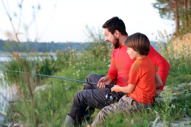 Photo of Emotional father and his little son fishing together outdoors