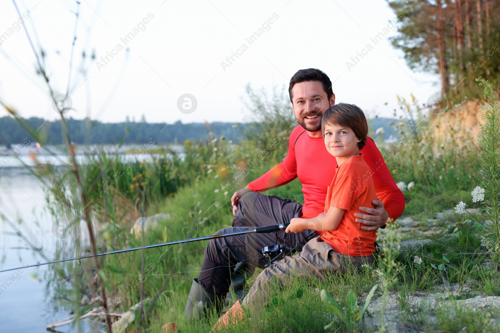 Photo of Happy father and his little son fishing together outdoors
