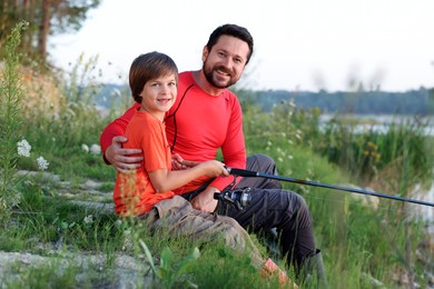 Photo of Happy father and his little son fishing together outdoors