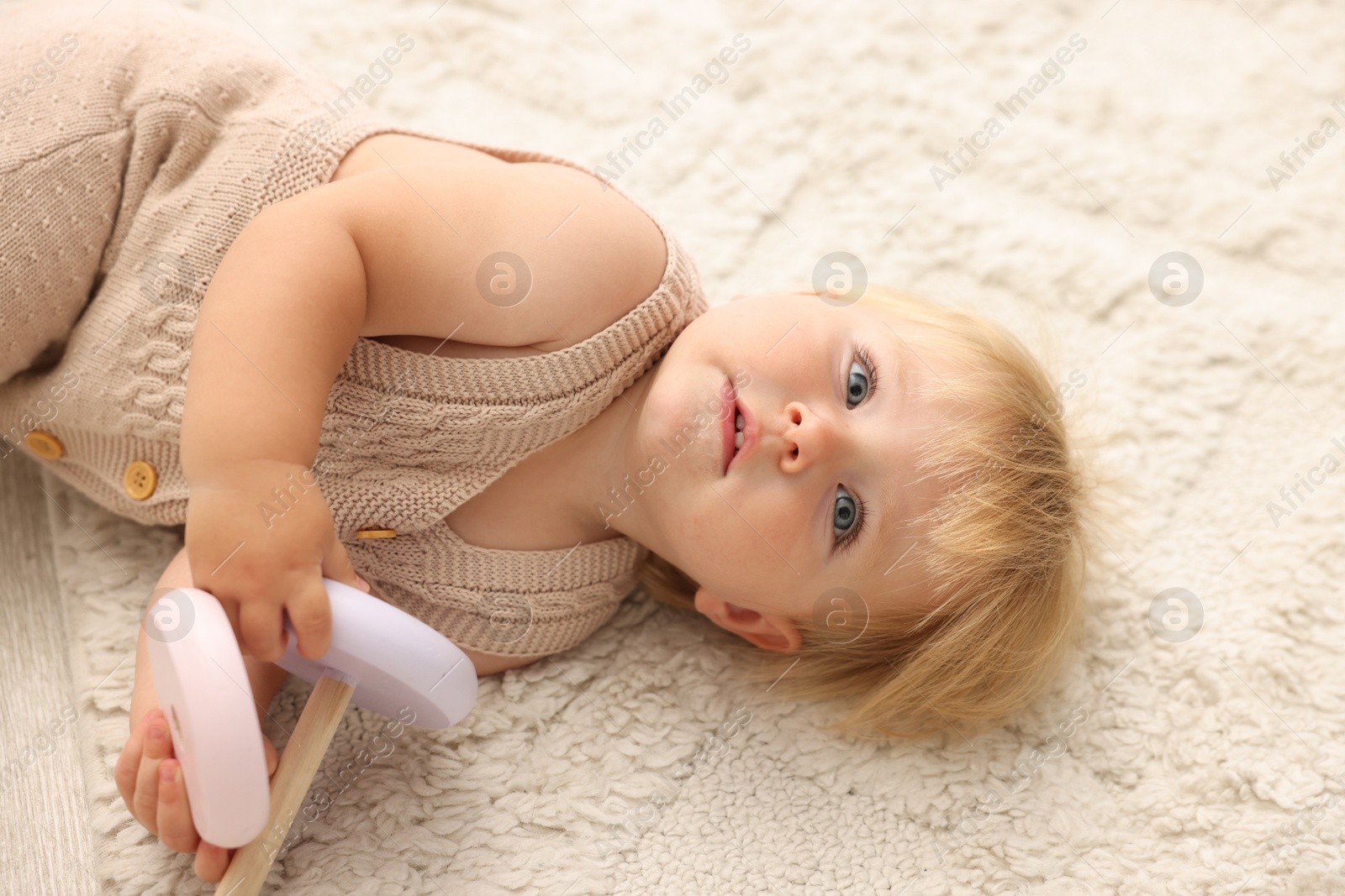 Photo of Cute baby lying with toy on floor at home
