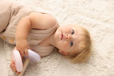 Photo of Cute baby lying with toy on floor at home