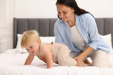 Photo of Smiling mother with her cute baby on bed at home