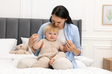 Photo of Mother kissing her cute baby on bed at home