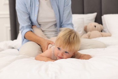Photo of Cute baby and her mother on bed at home, closeup