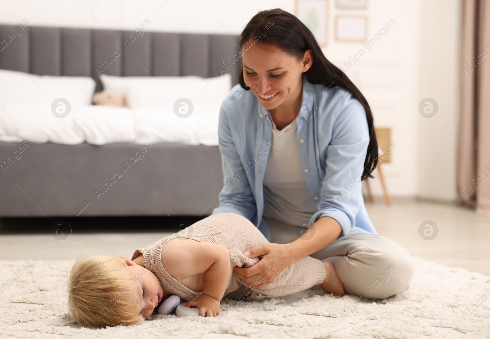 Smiling mother with her cute baby on floor in bedroom Photo of Smiling mother with her cute baby on floor in bedroom