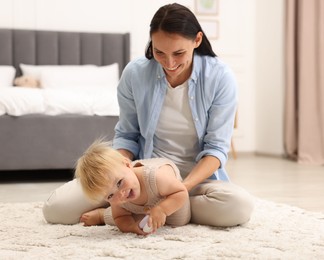 Photo of Smiling mother with her cute baby on floor in bedroom